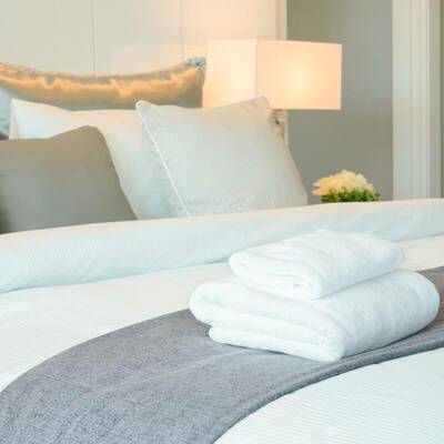 Bettwäsche und flauschige Handtücher auf einem breiten Bett